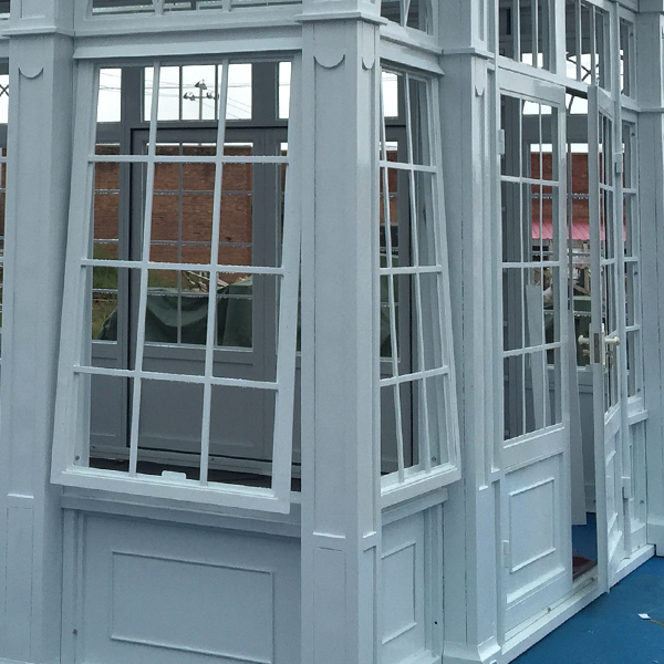 Multi-grid steel casement window and carved pillar detail of white Victorian conservatory