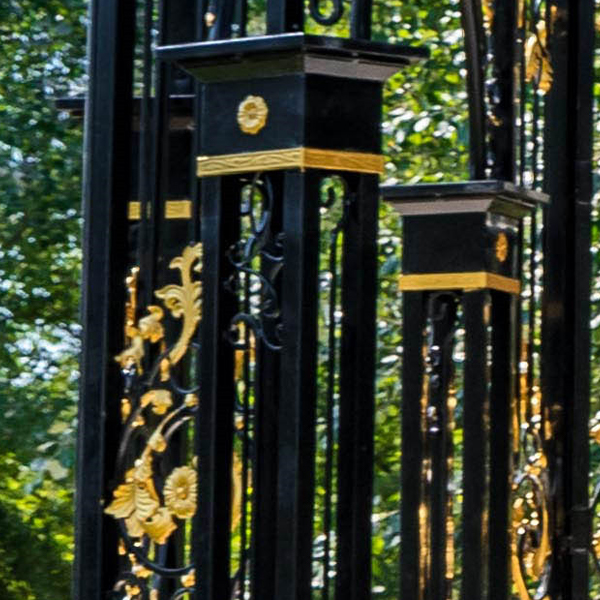 Square topped black iron pillar with golden trim and floral carvings of gazebo