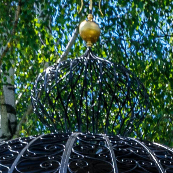 Shiny golden ball finial fixed on the apex of wrought iron gazebo dome