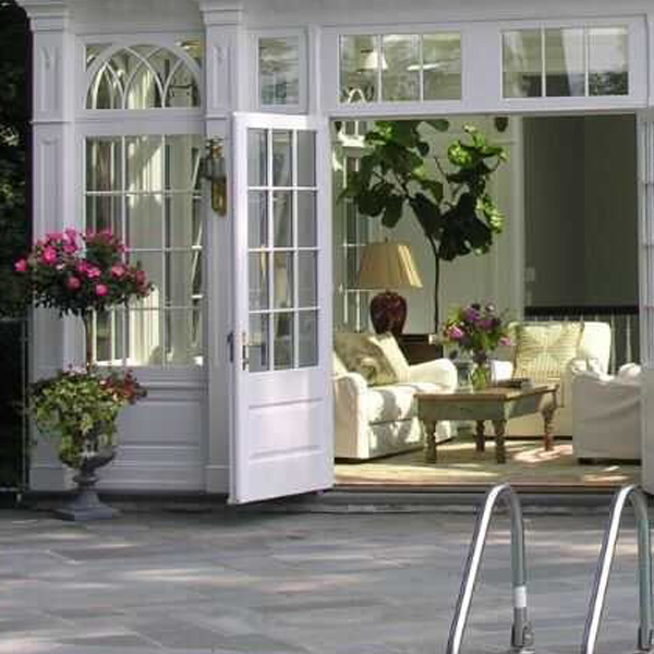 Open French doors reveal cozy interior lounge inside Victorian garden sunroom