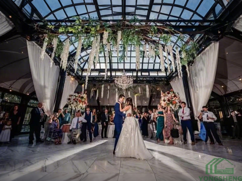 Bride and groom first dance inside large glass conservatory wedding hall
