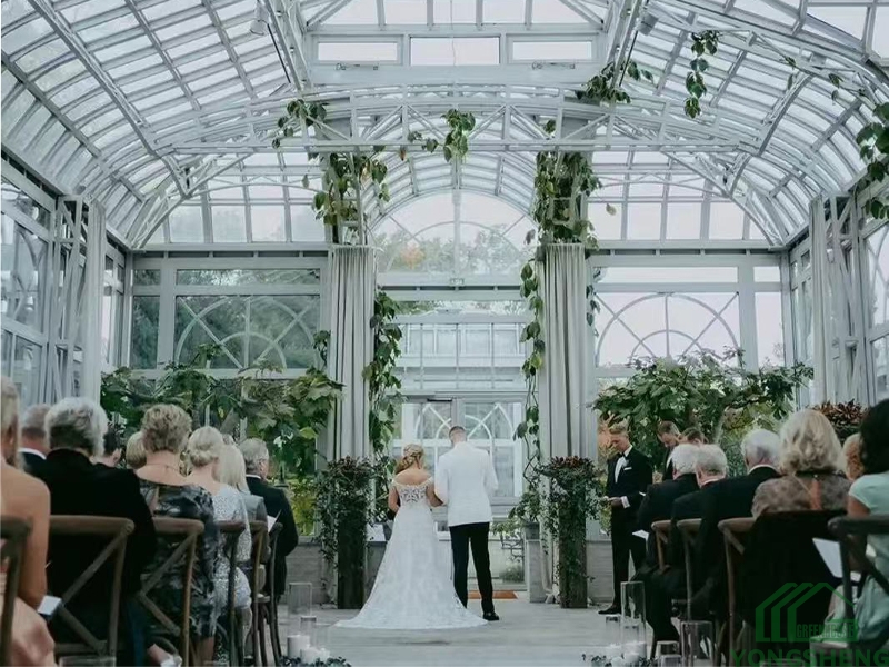 Glass conservatory interior for wedding ceremony with green vine decorations