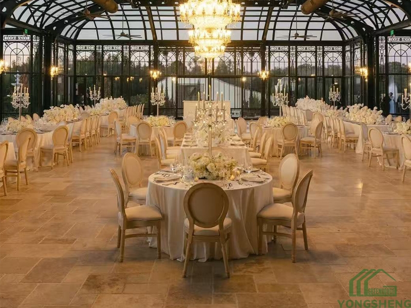 Spacious steel-framed glass pavilion with circular tables and outdoor lake view.