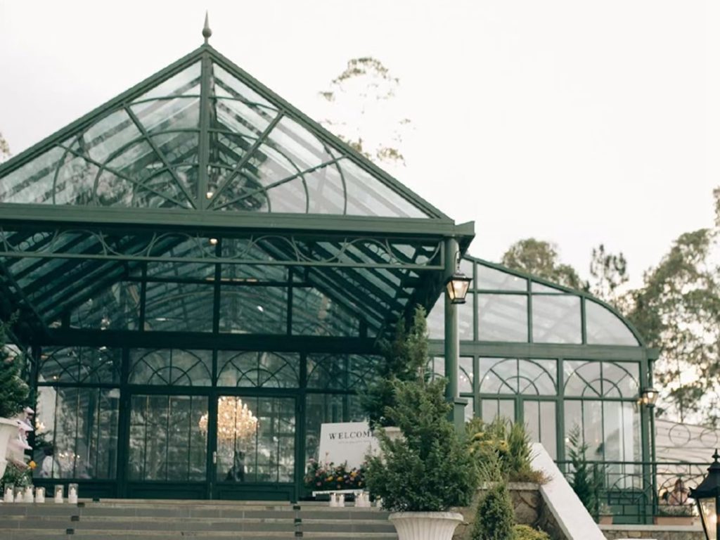 Side exterior shot of green victorian glass conservatory event venue with gable roof