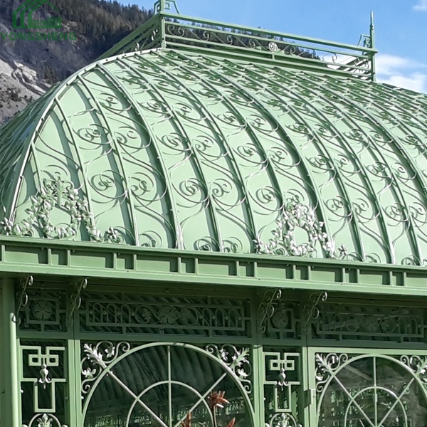 Close view of curved dome roof scroll ornament and arched window frame on green steel orangery