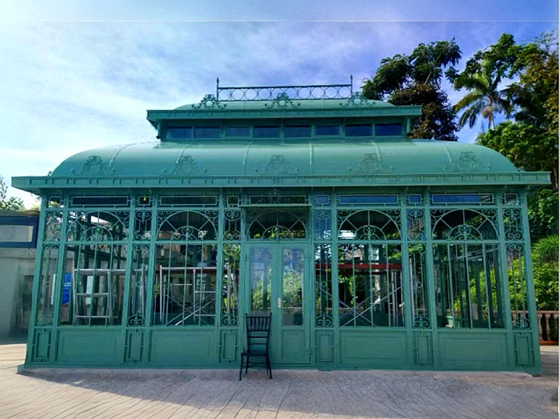 Green Victorian glass conservatory, vintage wrought iron sunroom greenhouse for garden and resort