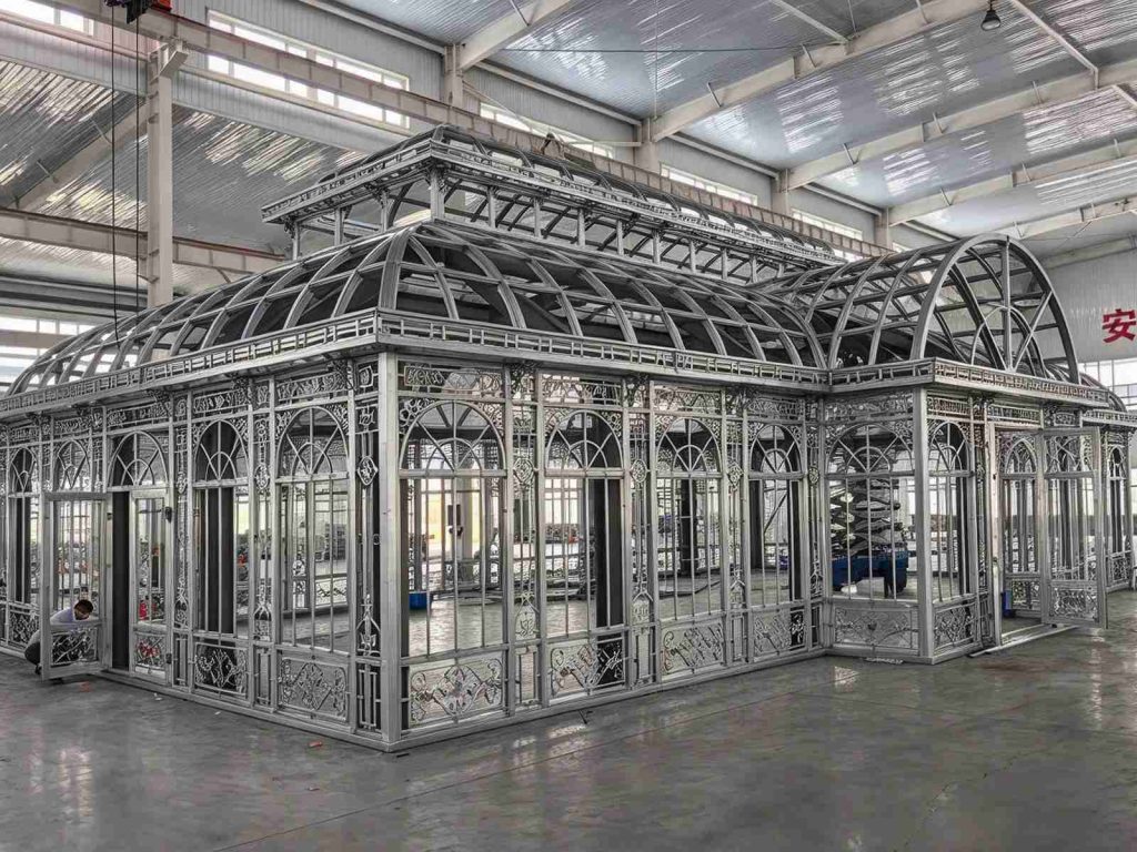 Side view of pre-assembled Victorian conservatory, decorative steel frame and arched roof inside factory