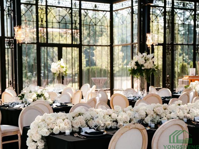 Black steel-framed glass hall with round tables and white floral centerpieces.