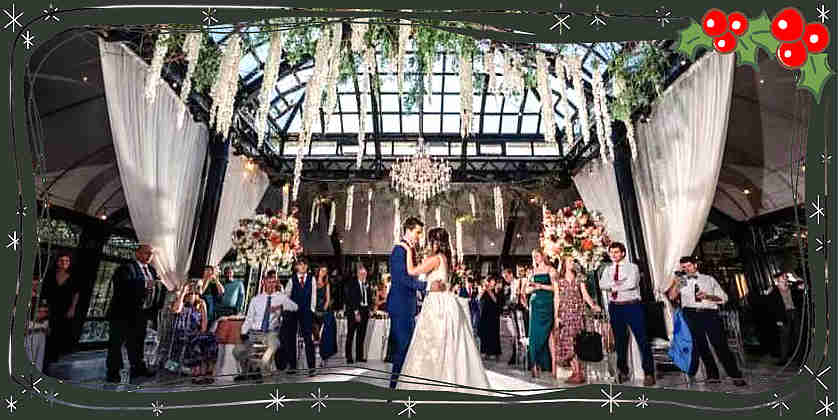 A couple exchanging vows under a floral arch in a grand Victorian greenhouse