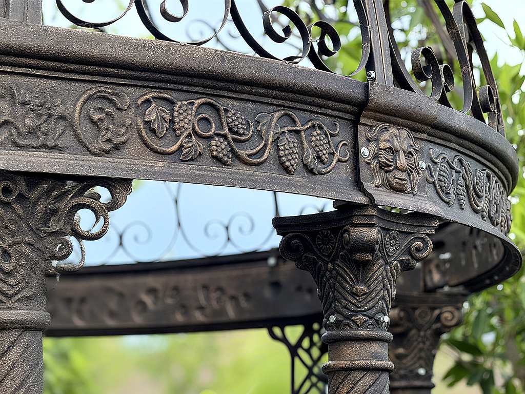 Close‑up of lion face and grape carvings on cast iron gazebo beam and column