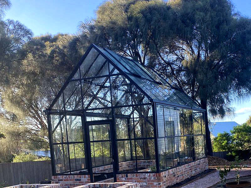 Side profile of Victorian gable greenhouse, black aluminum frame and tempered glass wall panels