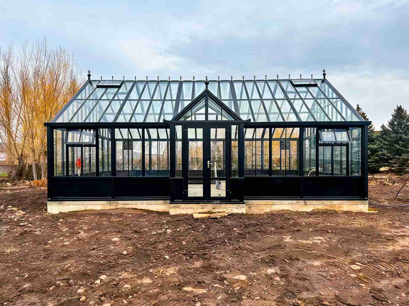 Freestanding large victorian glass conservatory built on concrete foundation in garden site