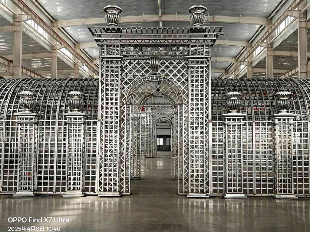 Front close‑up factory view of ornate galvanized steel trellis main gateway with dual arched tunnel sections