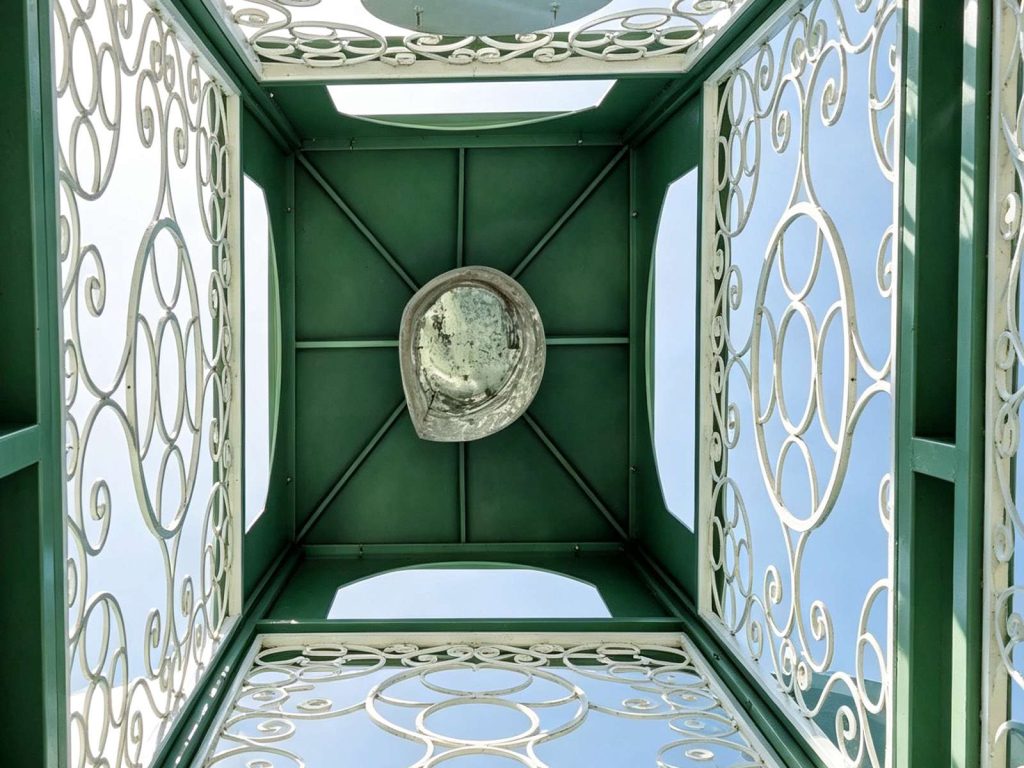 Close-up carved scroll wrought iron panel inside steel chapel clock tower powder coated surface