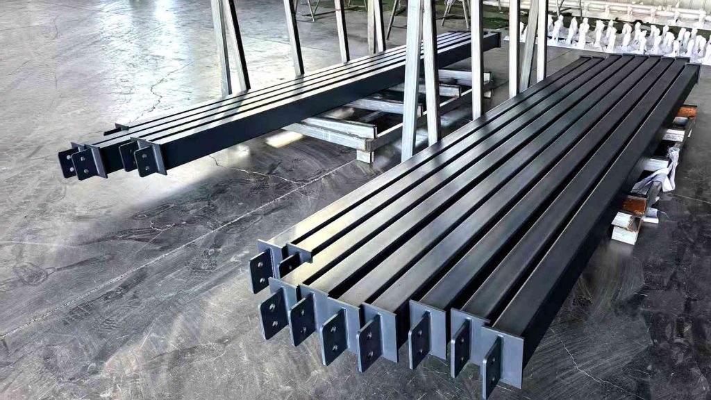 Heavy-duty H-beam steel supports for a 20x40m sunroom frame, pre-welded and stacked in a metal fabrication factory.