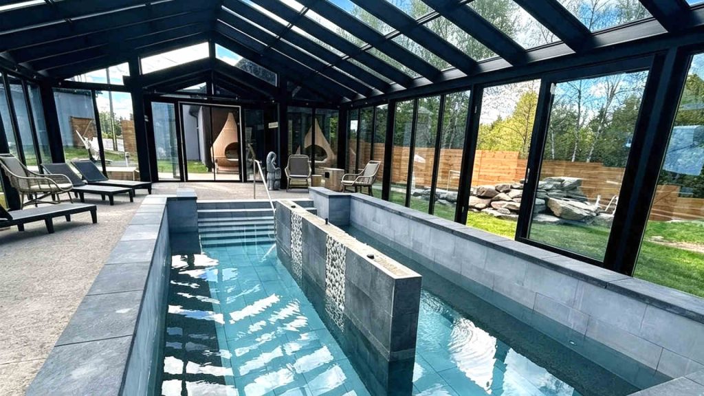 Indoor luxury spa sunroom with black frames and blue pool water.