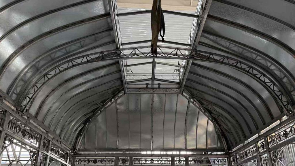 Interior arched roof truss of custom Victorian greenhouse inside manufacturing workshop