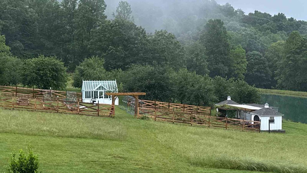 Panoramic view of english‑style greenhouse set within large East Tennessee property with lake and misty wooded hills