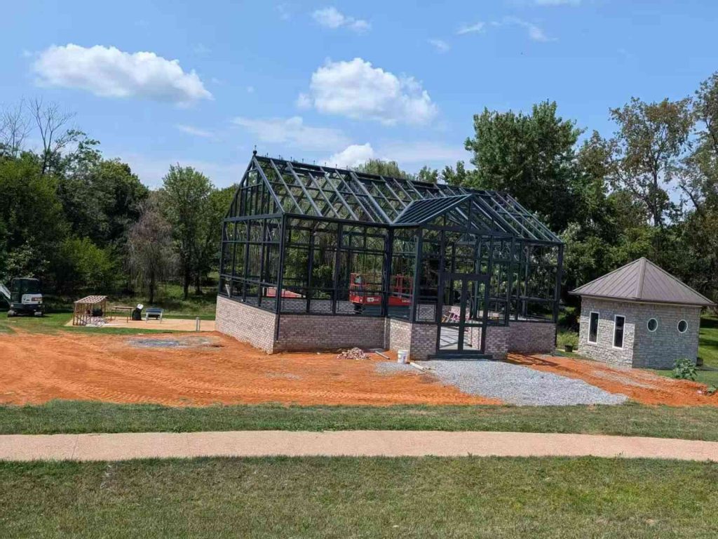 Victorian garden greenhouse frame build progress with clay brick base at residential garden construction site