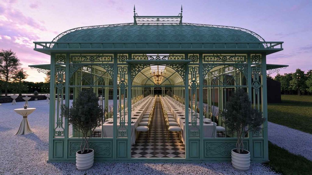 Mint green Victorian greenhouse exterior at sunset, ornate iron frame with glass panels, event dining setup inside